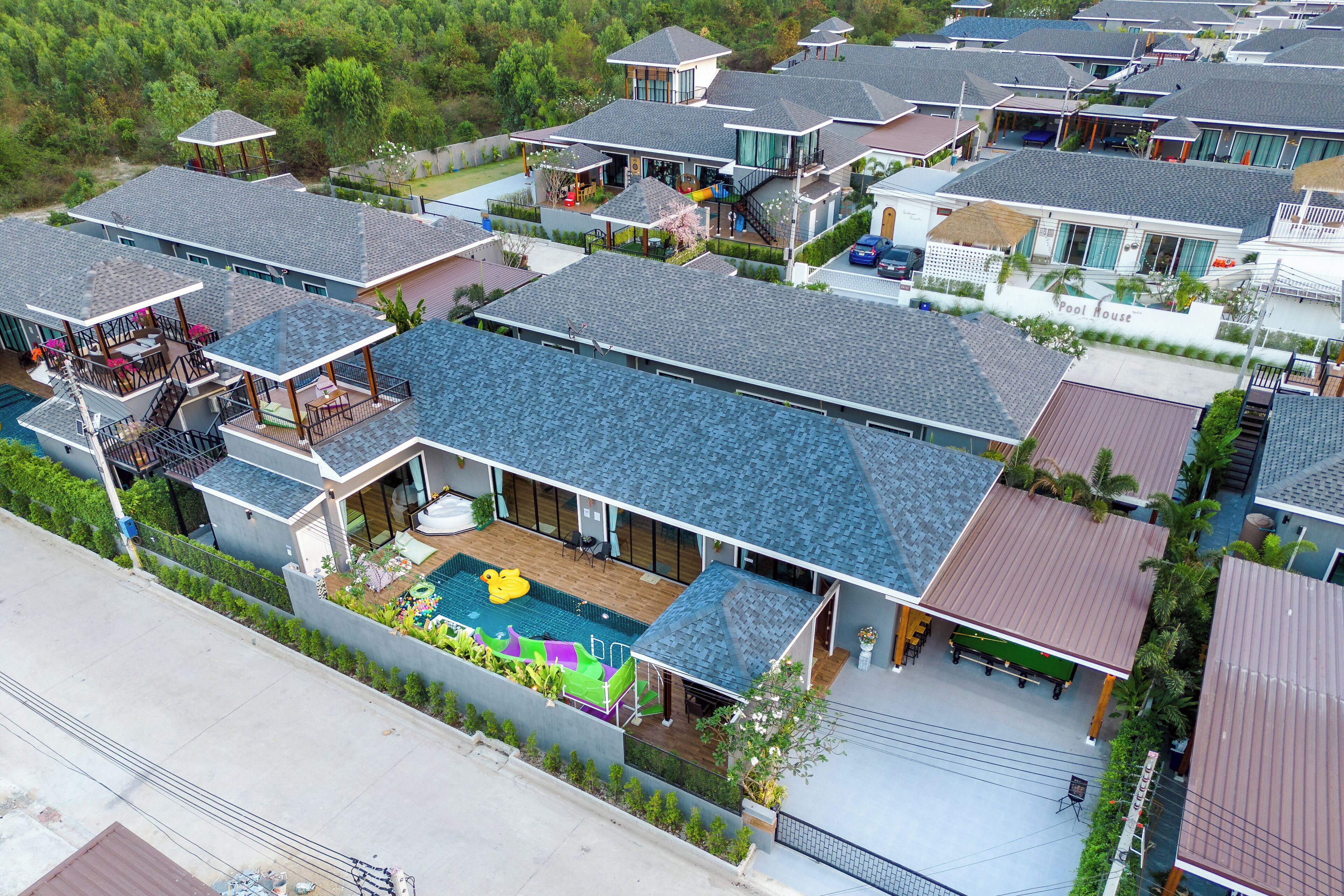 Zona residencial con varias casas, una piscina y un patio cubierto.