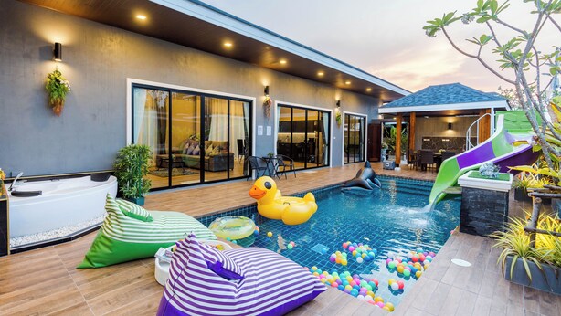 Un área de piscina al aire libre con tobogán, pato inflable y pelotas de colores.