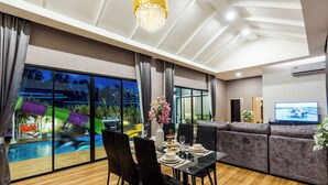 Una sala de estar moderna con comedor, ventanas amplias, piscina y televisor.