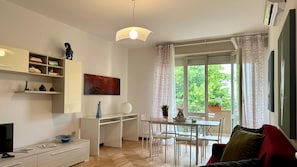A modern living space with a dining area, a white desk, and a television on a cabinet. - At Deborah’s Place – More Than Just Accommodation (Padova)