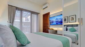 A hotel room with a large bed, a television, and a desk with a chair. - Villa Sandalwood - Seminyak (Seminyak)