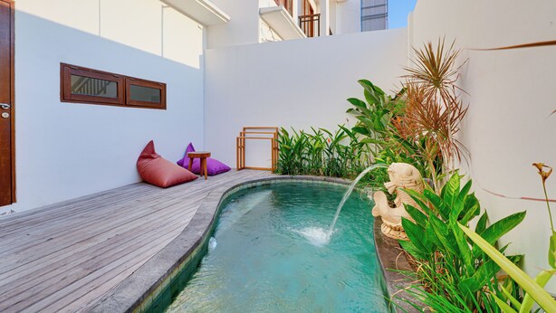 A small pool with a wooden deck, surrounded by plants and a statue. - Villa Sandalwood - Seminyak (Seminyak)