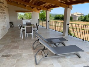 A covered patio area with a table and chairs, a bar sign, and a view of the landscape.