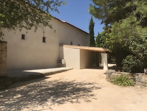 Un bâtiment doté d’une entrée abritée, d’une allée gravillonnée et entouré de verdure.
