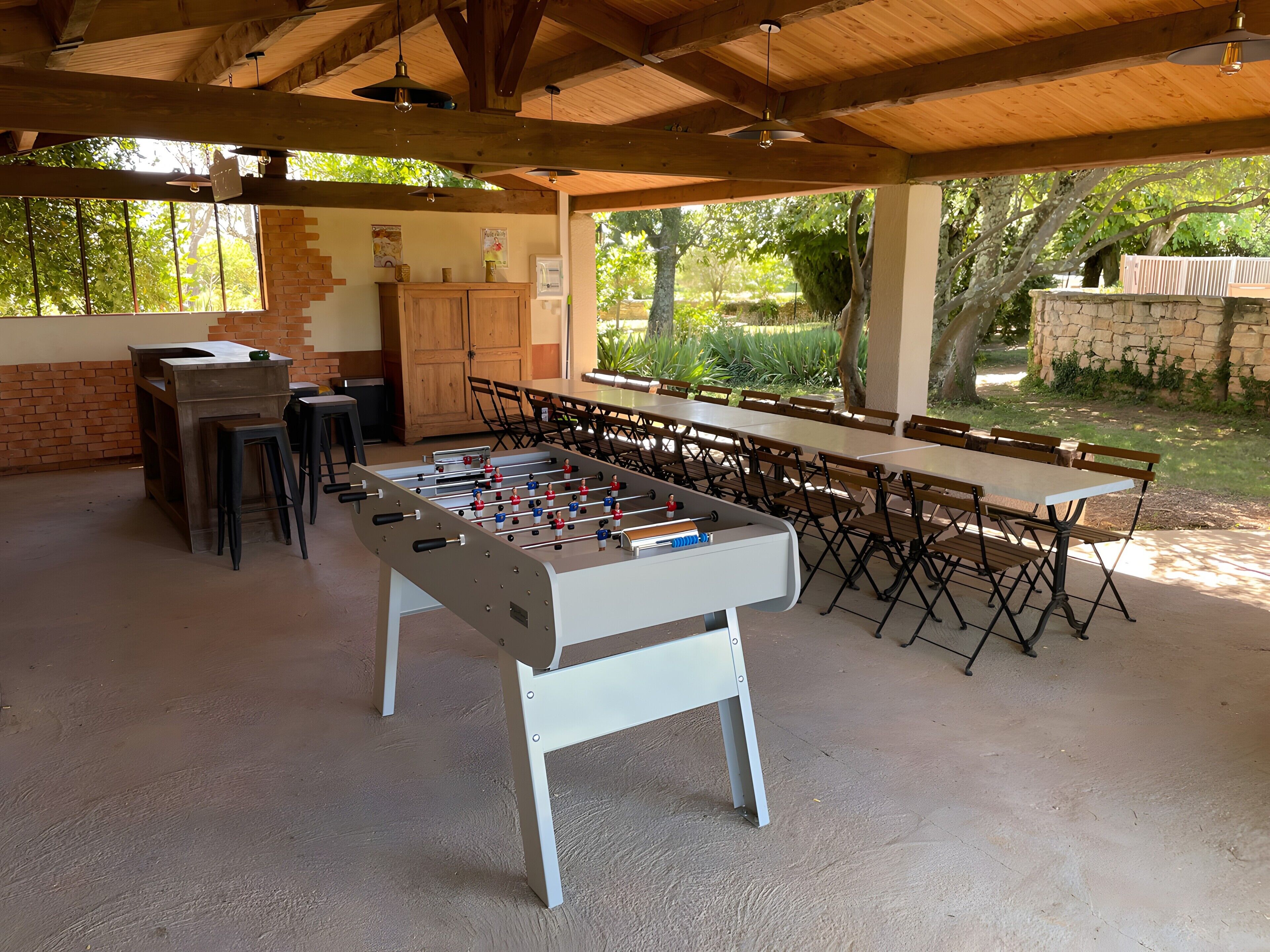 Espacio interior con mesa de futbolín, asientos y pared de ladrillo.