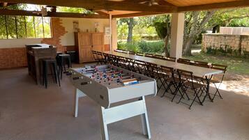 Espacio interior con mesa de futbolín, asientos y pared de ladrillo.