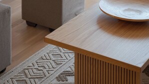 A modern living room with a wooden coffee table, a grey ottoman, and a patterned rug. - Athenian Hillside Apartment, Apartment (Athens)