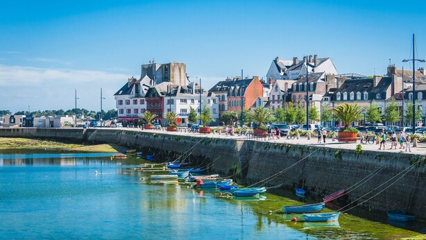 Eine Küstenstadt mit historischen Gebäuden, einer Promenade und Booten, die am Kai vor Anker liegen.