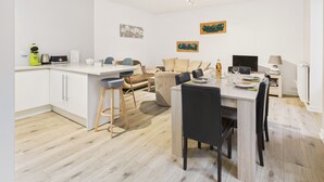 Eine moderne Küche mit Essbereich, einer Couch und einem Fernseher.