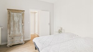 Ein Schlafzimmer mit Holzschrank, Bett mit weißer Decke und Nachttisch mit Lampe.