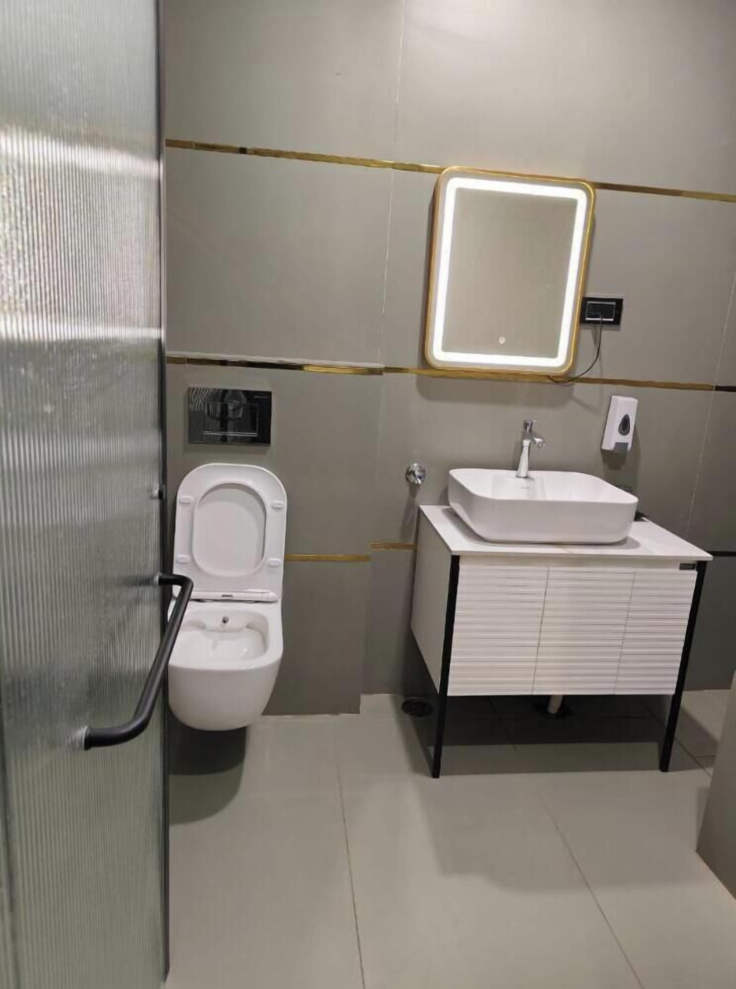 A modern bathroom with a toilet, sink, and mirror.