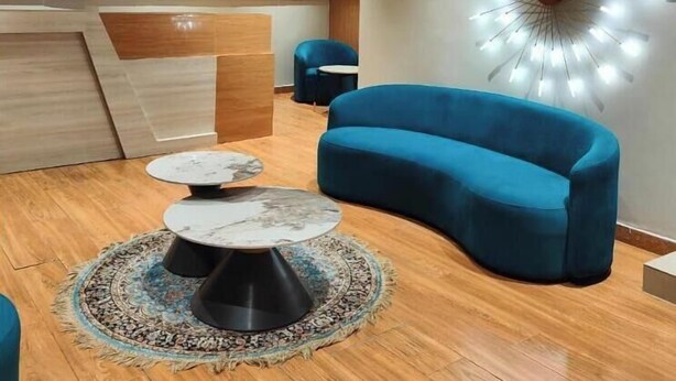 Una sala de estar moderna con un sofá azul, una mesa de centro redonda y una lámpara de techo original.