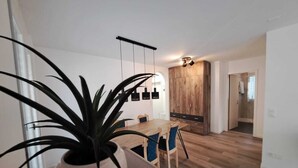 A modern dining area with a wooden table and chairs, a potted plant, and a large wardrobe in the background. - Luisiana (Minusio)