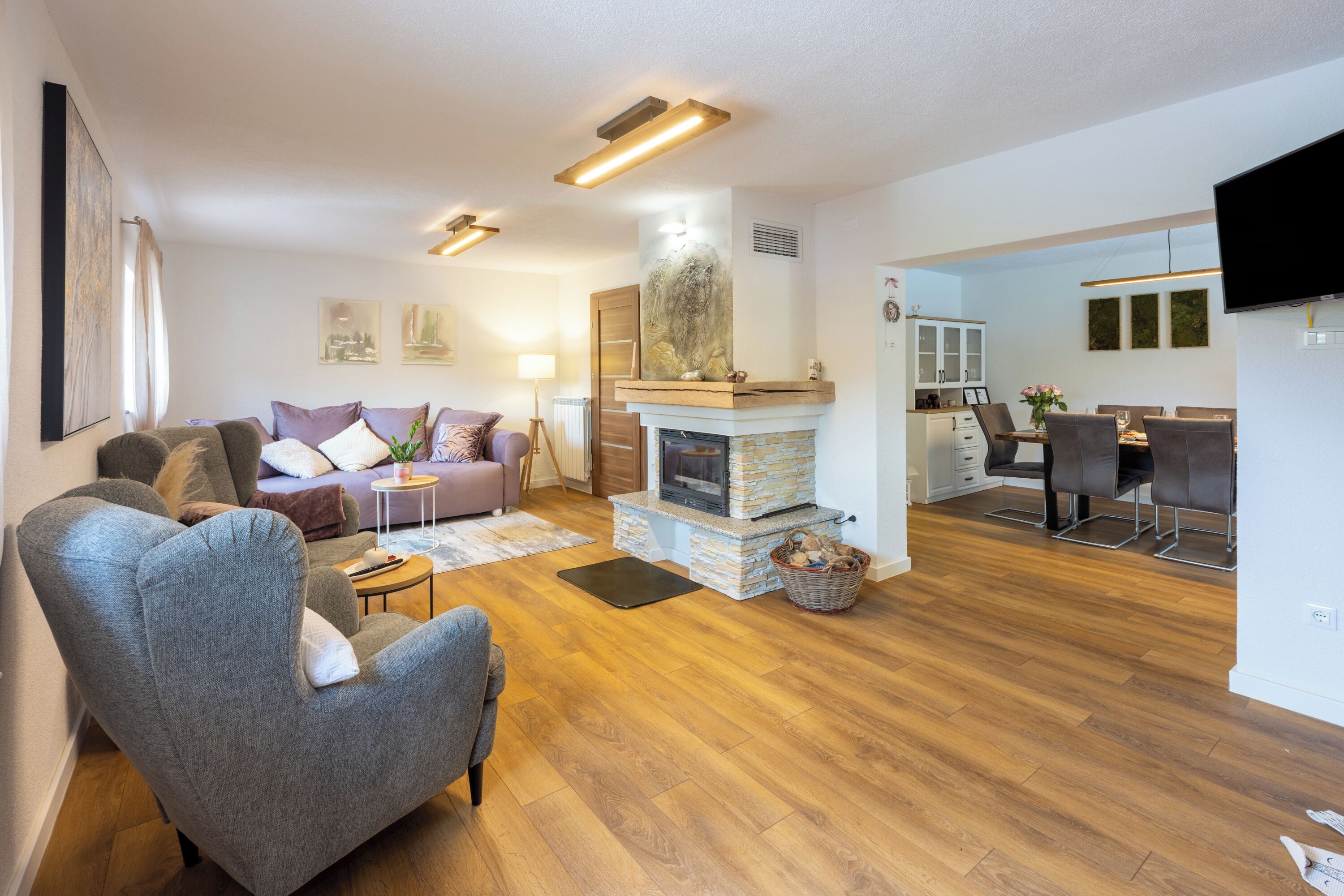 A modern living room with a fireplace, a dining area, and a kitchen.
