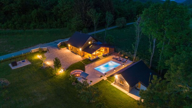 Une grande maison avec une piscine, entourée d’une pelouse bien entretenue et d’arbres.