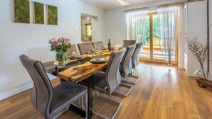 Un coin repas avec une table en bois, six chaises et un vase de fleurs.
