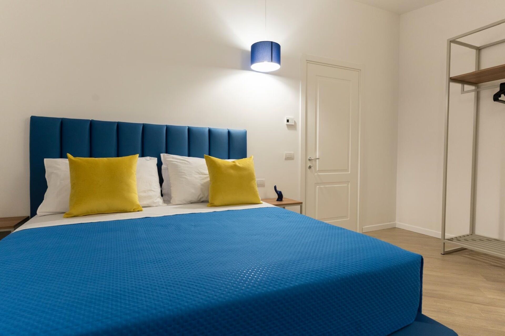 Een slaapkamer met een groot bed, een hoofdbord en een nachtkastje met een lamp.