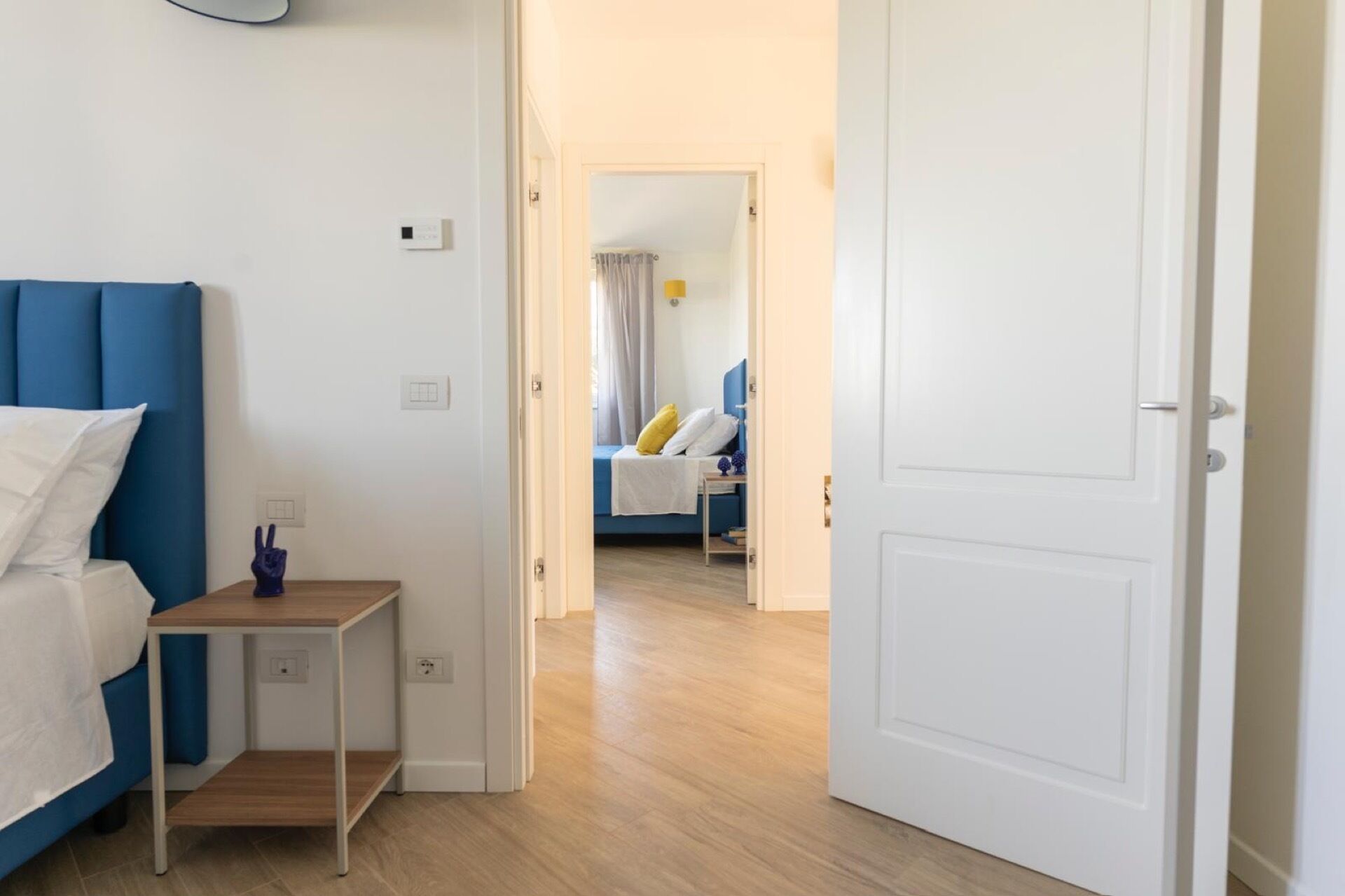 Une chambre d’hôtel avec un lit, une table de chevet et une porte donnant sur une autre pièce.