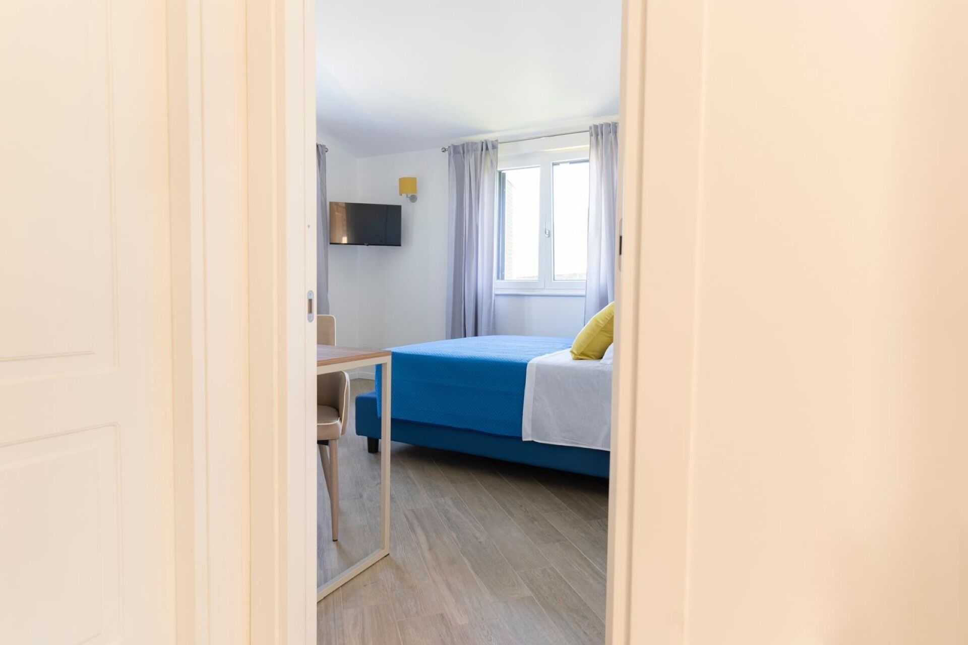 Un dormitorio pequeño con una cama individual, un escritorio y una televisión.