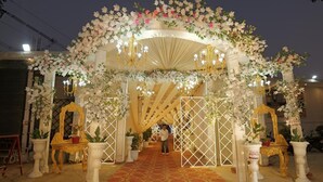 An ornate entrance with floral decorations and chandeliers, leading to a corridor. - The Golden Nacre Palace (Bharthana)