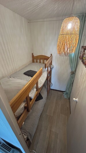Ein kleiner, kompakter Raum mit einem Etagenbett, einer Pendelleuchte und einem Vorhang.