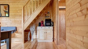 A wooden interior with a staircase, a kitchen area with appliances, and a dining table. - Chalet in Périgord Vert (Sainte-Croix de Mareuil)
