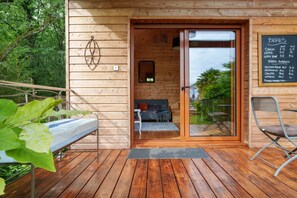 Une cabane en bois dotée d’une porte coulissante en verre qui donne sur un intérieur comprenant un canapé et une table.