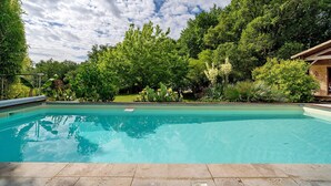 A rectangular swimming pool with clear blue water, surrounded by lush greenery and trees. - Chalet in Périgord Vert (Sainte-Croix de Mareuil)