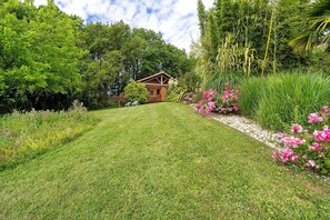A wooden cabin surrounded by lush greenery and flowering plants.