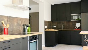 A modern kitchen with dark cabinetry, a wooden countertop, and a built-in oven. - Piscine/ Proche mer et village / Carry Le Rouet (Carry-le-Rouet)