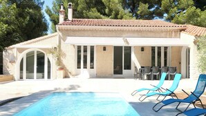 A poolside area with a clear blue pool, lounge chairs, and a covered patio with outdoor seating. - Piscine/ Proche mer et village / Carry Le Rouet (Carry-le-Rouet)
