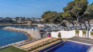 A coastal property with a swimming pool, marina, and houses in the background. - Villa de Luxe Front de Mer Avec Piscine villa Romanella (Carry-le-Rouet)