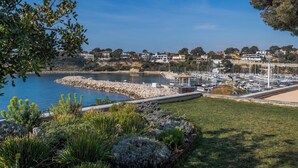 A marina with boats, a rocky breakwater, and houses in the background. - Villa de Luxe Front de Mer Avec Piscine villa Romanella (Carry-le-Rouet)