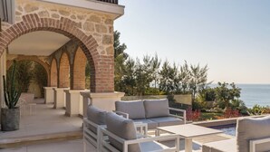 A patio with outdoor furniture, a stone archway, and a view of the sea. - Villa de Luxe Front de Mer Avec Piscine villa Romanella (Carry-le-Rouet)