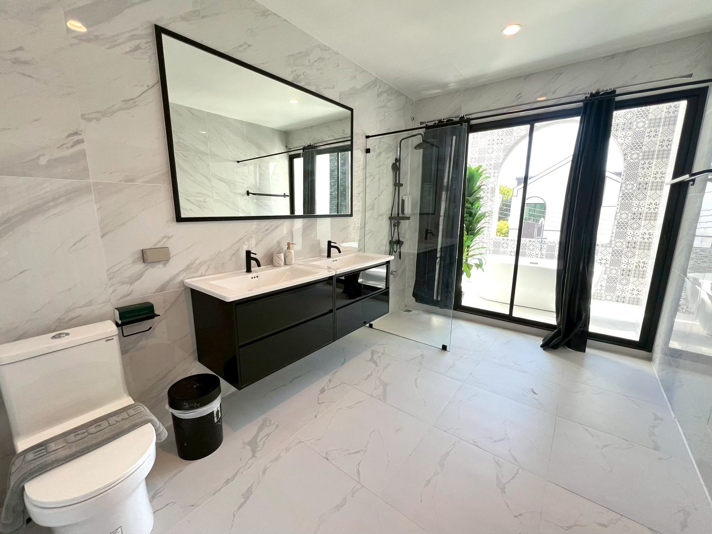 A modern bathroom with a large mirror, a white sink, and a toilet.