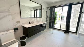 A modern bathroom with a large mirror, a white sink, and a toilet.