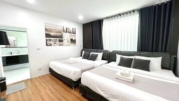 A modern hotel room with two beds, a bedside table, a mirror, and a wall with framed pictures.