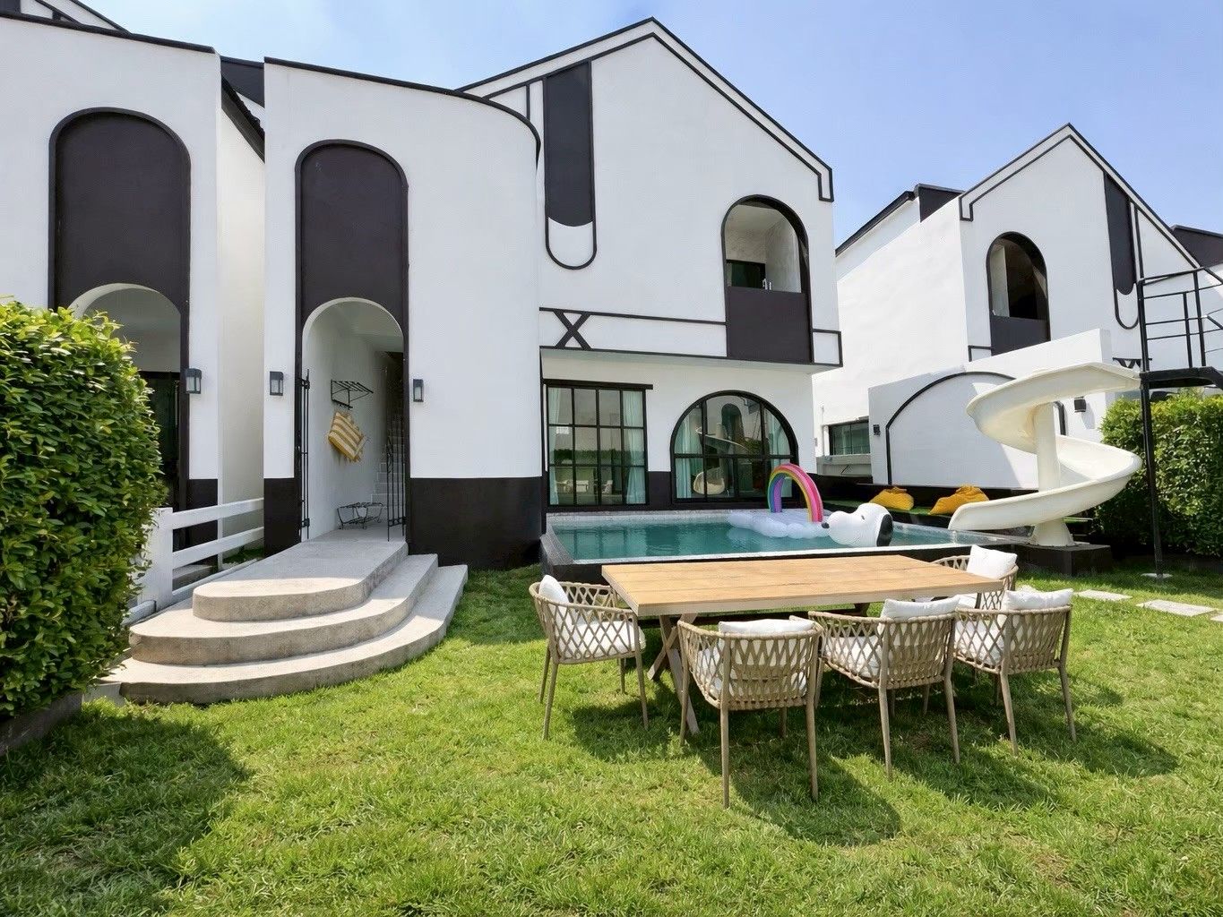 A modern house with a swimming pool, outdoor seating, and a unique spiral slide.