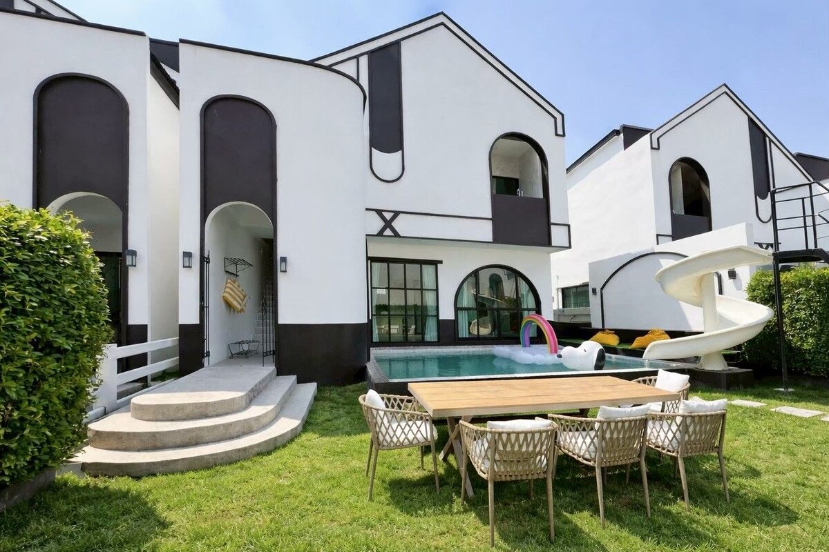 Una casa moderna con piscina, mobiliario exterior y un tobogán espiral único.