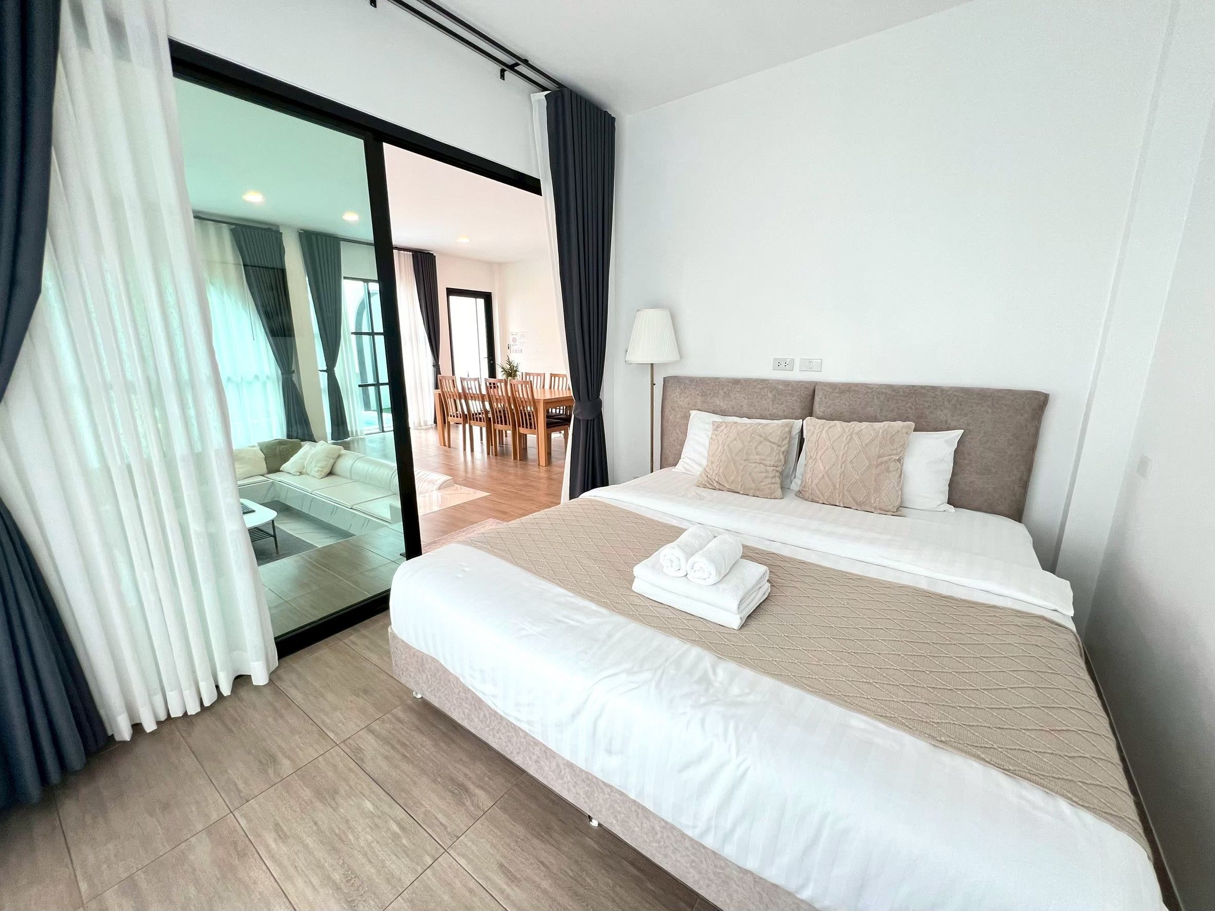 A hotel room with a bed, a sofa, and a view of a dining area.