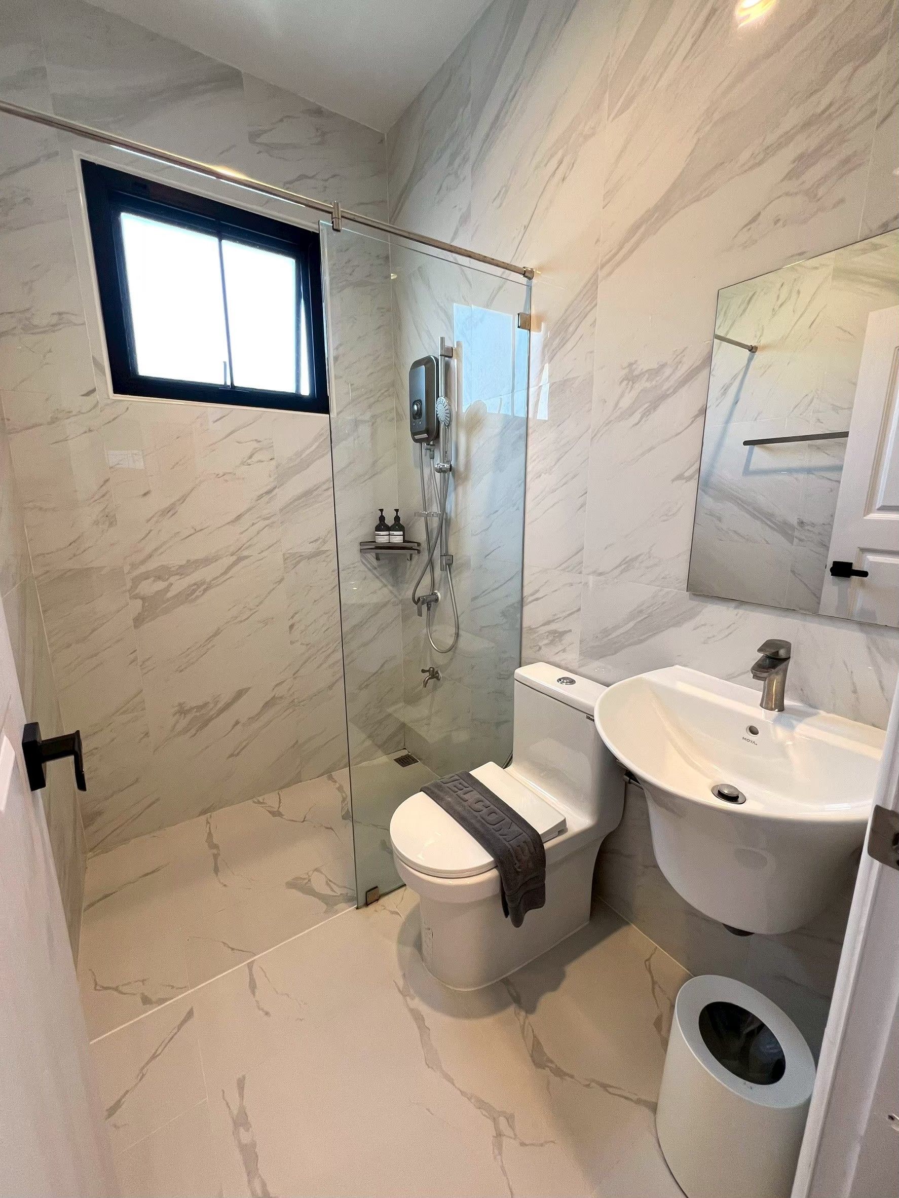 A bathroom with a glass-enclosed shower, a toilet, and a sink.