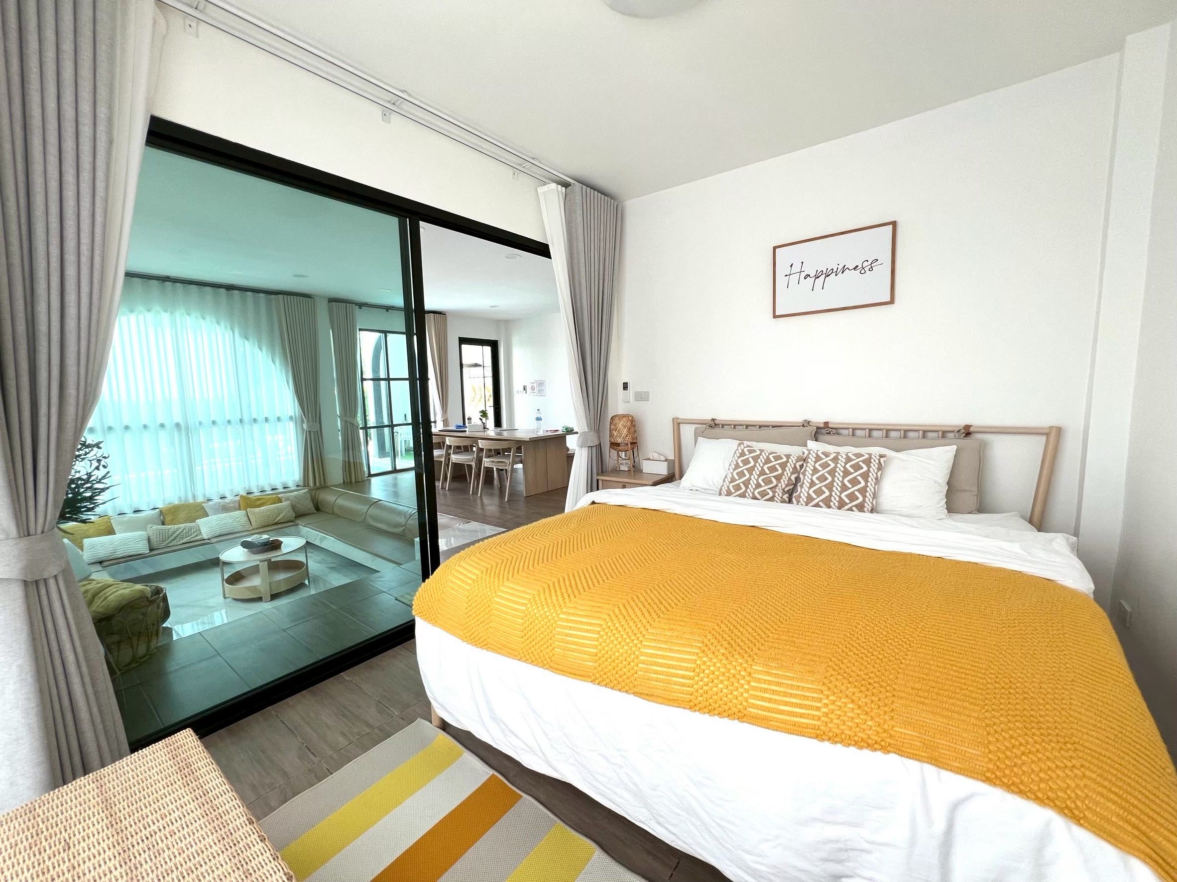 A hotel room with a large bed, a sliding glass door leading to a balcony, a small desk, and a wall-mounted sign.