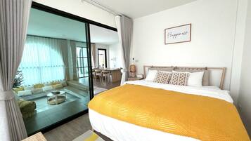 Een hotelkamer met een groot bed, een glazen schuifpui naar een balkon, een klein bureau en een bordje op de muur.