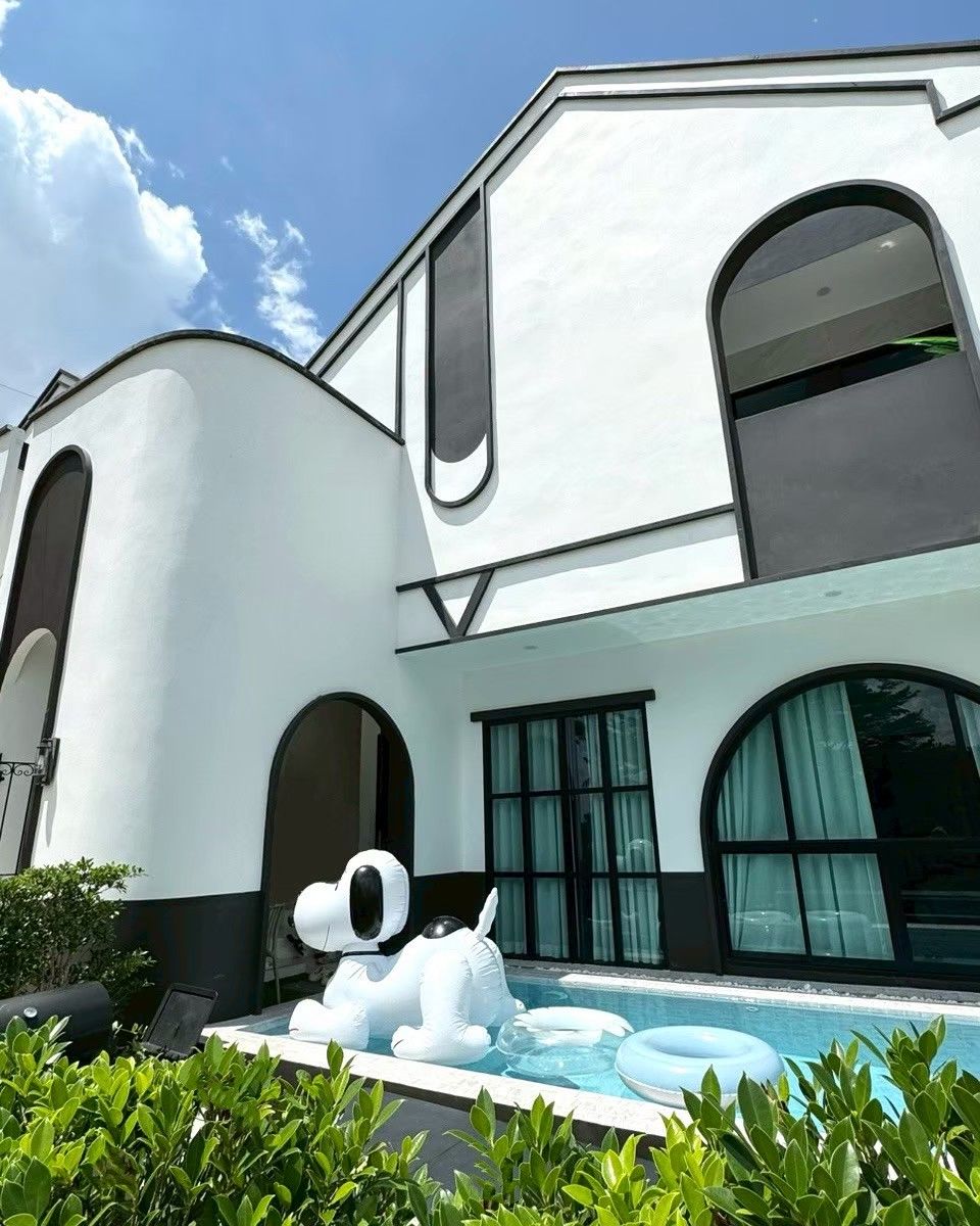 A modern building with a swimming pool, a large inflatable dog sculpture, and a laptop on the patio.