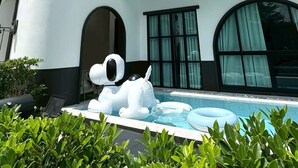 Un edificio moderno con piscina, una escultura inflable de perro grande y una computadora portátil en el patio.