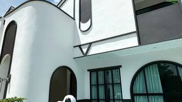 A modern building with a swimming pool, a large inflatable dog sculpture, and a laptop on the patio.