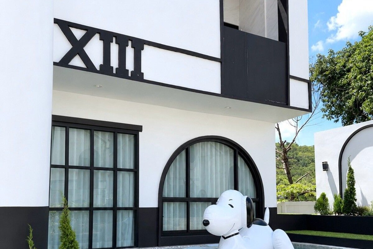 Un edificio moderno con una amplia fachada blanco y negro, piscina y una gran escultura inflable de un perro.