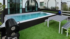 Una casa moderna con piscina, mobiliario de exterior y zona de barbacoa.