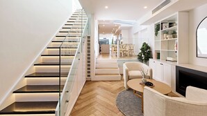 En modern inredning med en trappa, ett vardagsrum med en soffa, ett soffbord och en öppen spis.