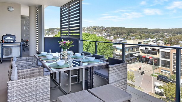 A balcony with outdoor furniture, a grill, and a view of the cityscape. - Oceanview Penthouse Caves Beach (Caves Beach)